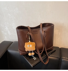 Détail du sac cabas marron foncé avec surpiqûres et breloque monstre en peluche