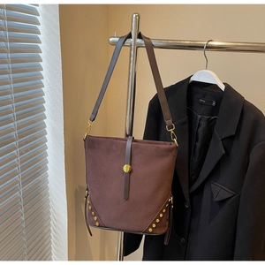 Detailed view of brown suede bucket bag featuring gold rivets and decorative metal buckle