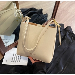 Détail du sac seau en cuir beige avec boucles dorées et inscription New York élégante