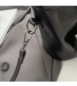 Dettaglio di una borsa in pelle nera che mostra la chiusura in metallo argento e la tracolla