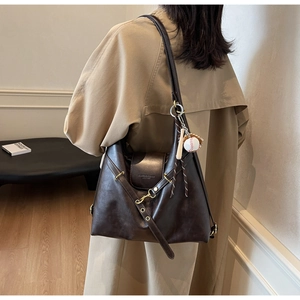 Detalle del bolso tote marrón oscuro retro con textura de cuero y colgante de béisbol
