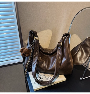 Detailed close-up of dark brown vintage faux leather tote with adjustable strap and bear charm