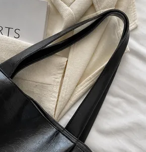Close-up of high-gloss wrinkled black leather material and slim straps on the tote bag