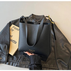Détail d'un sac cabas en cuir grainé noir avec logo doré et boucle de sangle en métal