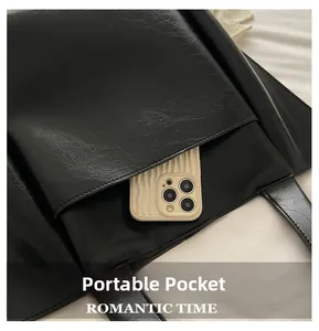 Detail of the black leather tote bag featuring a functional front portable pocket