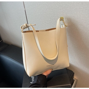 Détail d'un sac à bandoulière en similicuir crème avec boucles dorées et texte New York