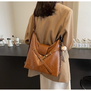 Detalle de un gran bolso tote de cuero marrón vintage con un colgante de béisbol en un modelo