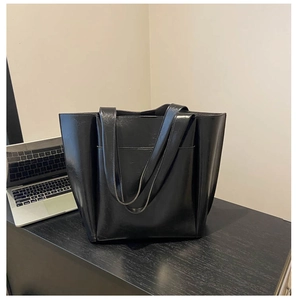 Close-up of black leather tote bag with wide shoulder straps and large capacity