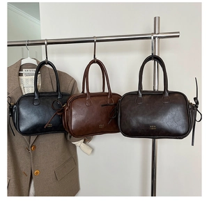 Three retro faux leather crossbody handbags in black and brown displayed on a rack