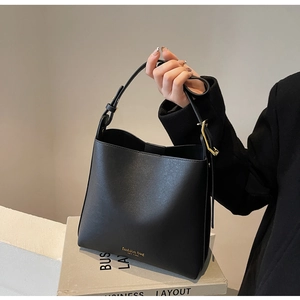 Détail du sac seau noir minimaliste avec lettrage doré et bandoulière réglable chic