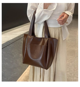 Detail showing large capacity brown tote bag with front pocket and oiled leather texture
