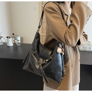 Detalle del bolso tote vintage negro con herrajes dorados y amuleto de guante de béisbol