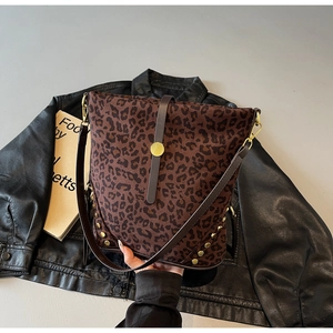Dettaglio borsa leopardata con rivetti dorati e tracolla su una giacca nera