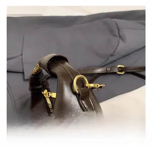 Close-up of golden metal zipper and hardware on a vintage dark brown leather handbag
