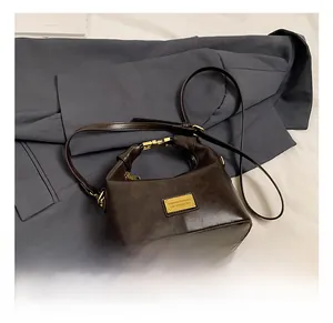 Detail of vintage brown leather handbag with gold buckle and twisted handle design