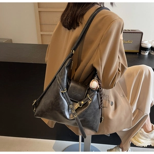 Detalle de bolso tote de cuero vintage negro con anillos de metal y colgante de béisbol