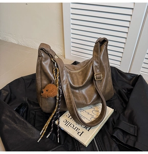Detail of retro dark brown leather tote bag with cute bear charm and metal buckle