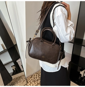 Detail of vintage coffee brown square handbag with gold logo and ribbon accent