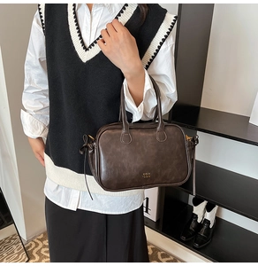 Detailed side view of a vintage dark brown leather handbag with side tie accents