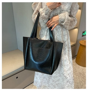 Close-up of black glossy crackle texture tote bag with front pocket and double handles