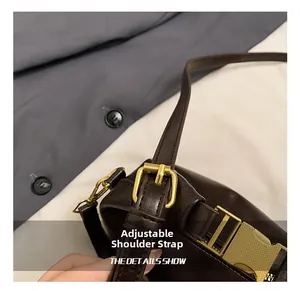 Detail of dark coffee leather handbag with adjustable gold-tone buckle strap