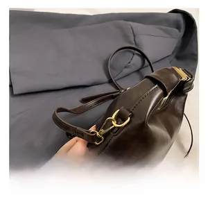 Detailed macro view of the premium golden metal swivel hook on a vintage brown leather bag