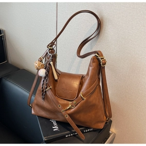 Detalle de bolso tote de cuero marrón retro con colgante deportivo y correas ajustables