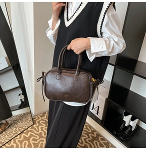 Detail of dark brown leather handbag featuring side bow ties and gold logo branding