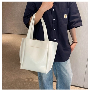 Detail of white large capacity tote bag with front pocket carried by a model