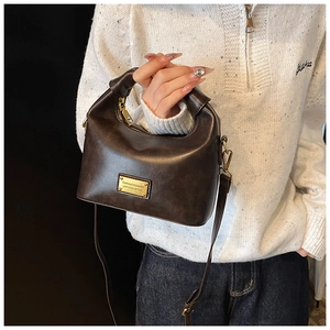 Detail of vintage dark brown handbag with gold hardware and removable shoulder strap