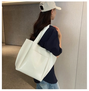 Detail of a white high-gloss leather tote bag with a functional front pocket
