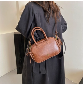 Macro shot of retro brown leather handbag showing gold lettering and side drawstring detail