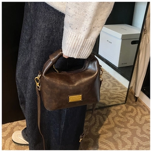 Detailed macro view of dark brown vintage handbag with gold hardware and top handle