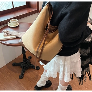 Close-up of large bucket bag with contrast leather trim and drawstring detail