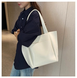 Detail view of the large off-white tote bag with a practical front pocket and sturdy handles