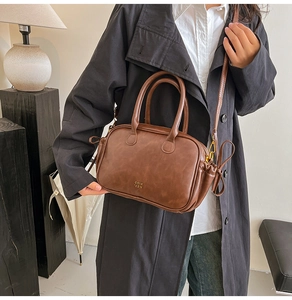 Detail view of brown PU leather bowling bag with gold logo and drawstring side texture