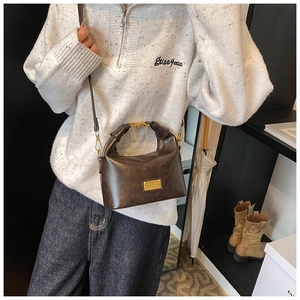 Detailed view of a dark brown vintage leather crossbody bag with gold buckle hardware