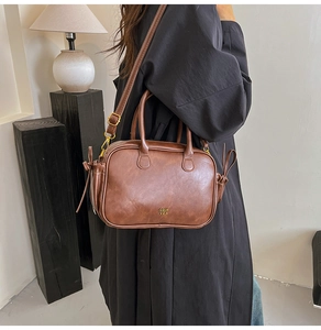 Close-up of vintage brown leather handbag with side drawstring bow and logo detail