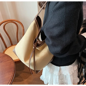 Detail view of large canvas bucket tote with leather trim worn on shoulder by model
