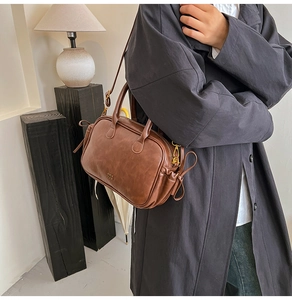Detail of vintage brown leather handbag featuring fine texture and adjustable strap