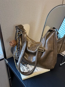 Deep brown faux leather dumpling bag with shoulder strap and plush bear charm