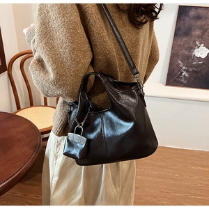 Dettaglio della borsa tote marrone scuro con trama in pelle oliata e ciondolo a busta