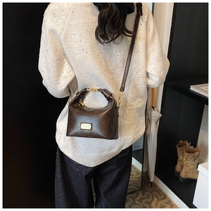 Detail view of a vintage dark brown faux leather crossbody bag with gold metal plaque