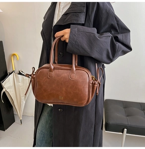Close-up of brown retro leather handbag with COIH 2DN logo and side bow detail