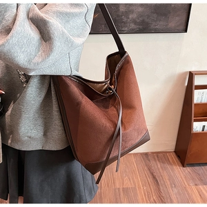 Detail of vintage brown suede tote bag with leather trim worn on the shoulder