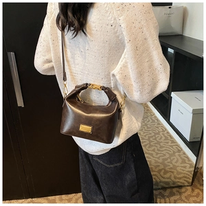 Detail of dark brown leather handbag with gold metal hardware and detachable strap