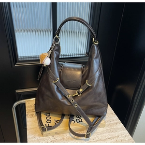 Detalle del bolso tote marrón oscuro con logotipo y colgante de béisbol decorativo