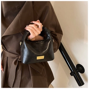Detail of a vintage black leather saddle bag with gold metal plaque and handle