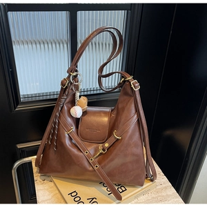 Detalle del bolso tote vintage marrón oscuro con relieve de moda y colgante de béisbol
