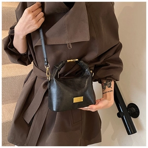 Detail of vintage black leather handbag with gold hardware and knotted top handle design
